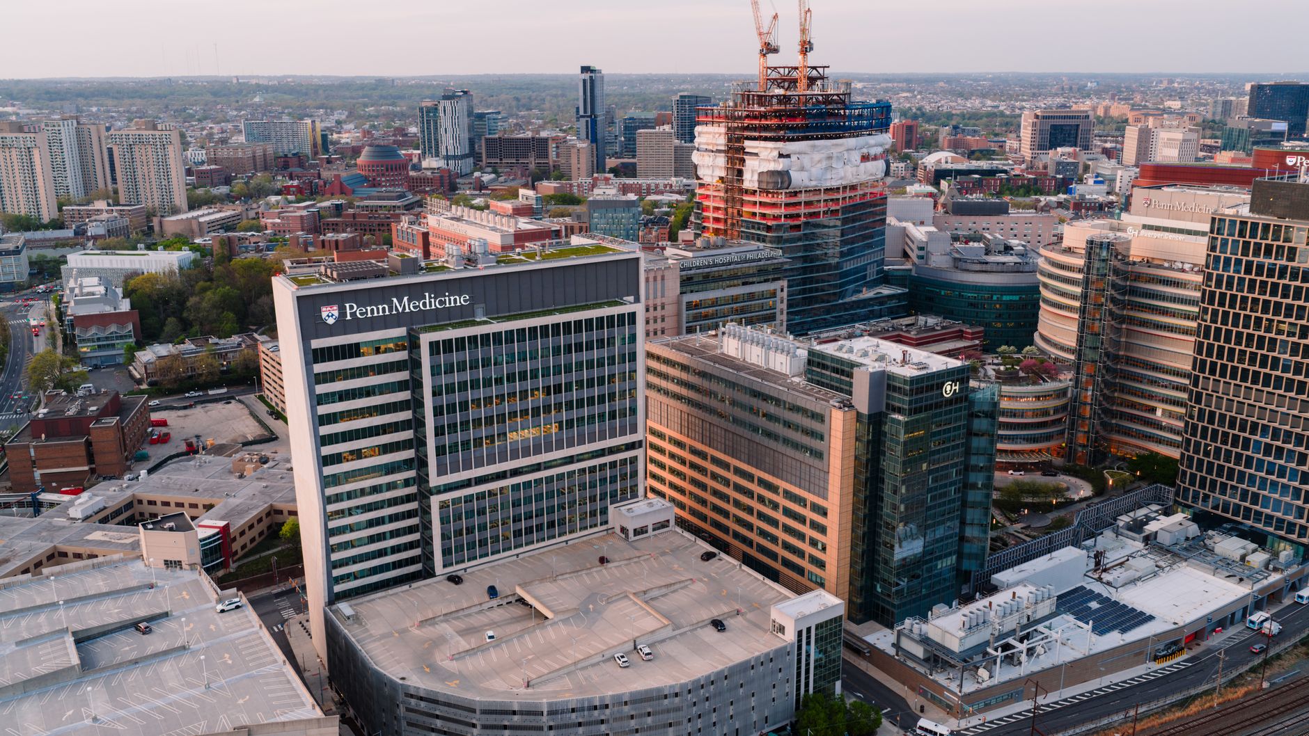 An aerial view of a traditional university campus blending into a modern corporate and residential development.
