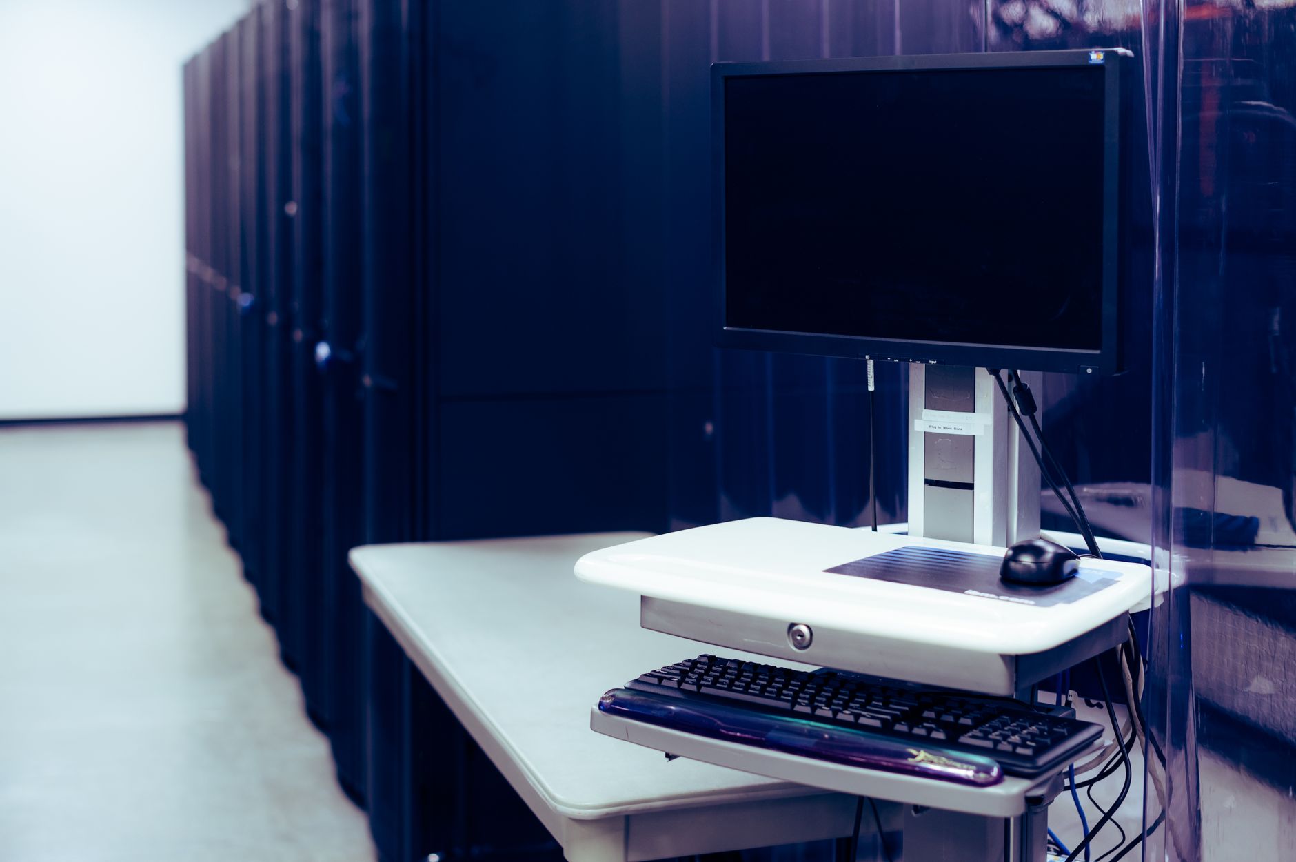 A vast, modern server room illuminated by soft blue and sterile white lights, with glass panels showing abstract medical data streams.
