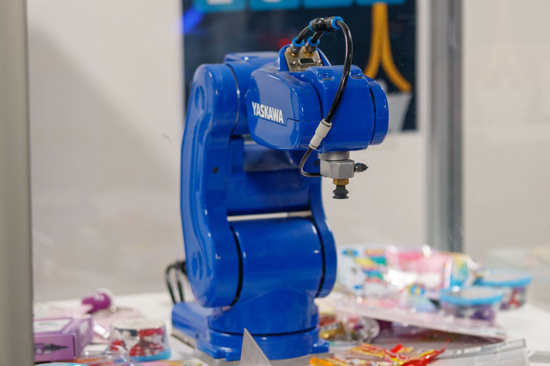A dusty robotic arm sitting idle in a corner while factory workers assemble parts in the background.