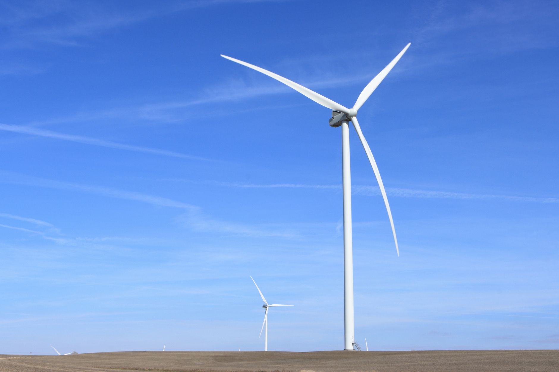 Heavy machinery processing decommissioned wind turbine blades in an industrial facility.